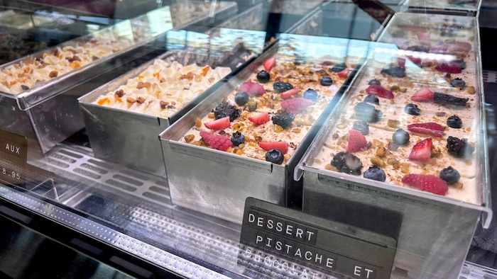 Des gâteaux dans un présentoir sont recouverts de fruits frais et de noix.