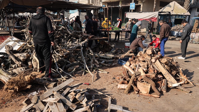 Des hommes ramassent des morceaux de bois dans la rue.