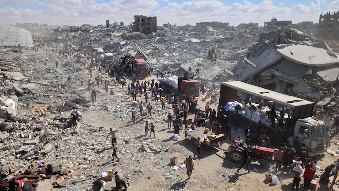 Des camions sont déchargés dans une zone totalement dévastée par les bombardements.