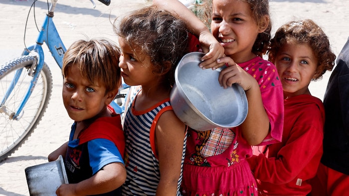 Des enfants attendent la distribution de nourriture, plats à la main.