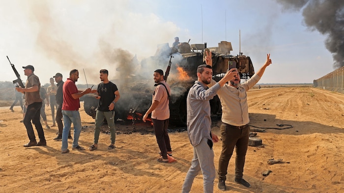 Palestiniens devant un char israélien en feu.