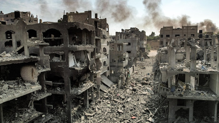 Vue aérienne de dizaines de bâtiments presque entièrement démolis, tandis que leurs débris recouvrent la rue.