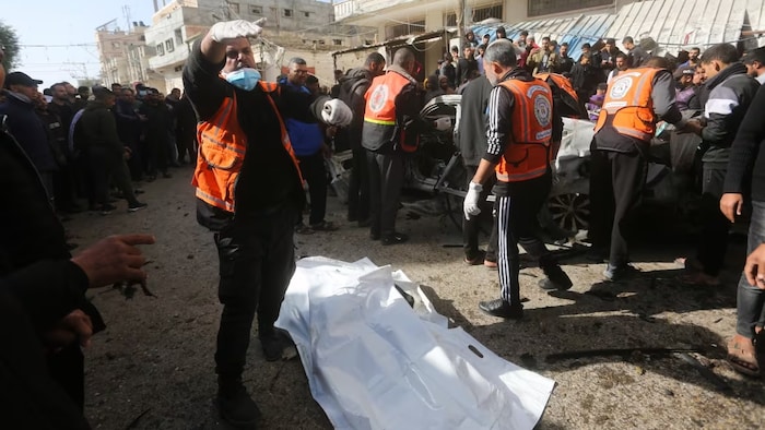 Filistinliler, 22 Aralık 2023'te İsrail'in Gazze Şeridi'nin Refah kentinde bir araca düzenlediği hava saldırısında öldürülen bir adamın cesedini çıkarıyor.