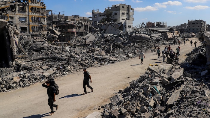 Des Palestiniens marchent devant les décombres de bâtiments détruits.