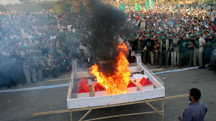 Des milliers de personnes rassemblées autour d'une maquette en feu.