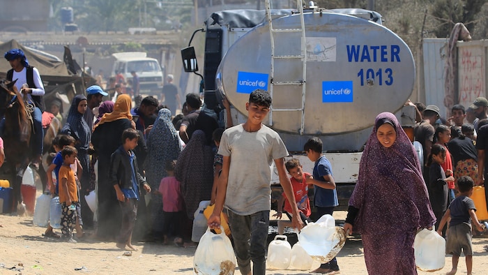 Des Palestiniens récupèrent de l'eau d'un camion de l'ONU à Deir Al-Balah, au centre de la bande de Gaza.