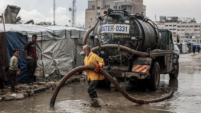 Un homme pompe de l'eau avec un camion de pompage.