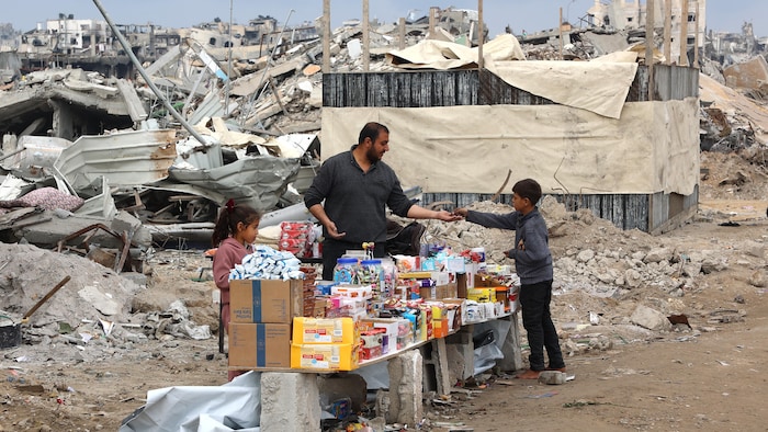 Un homme et une fillette vendent des aliments à un garçon entre les décombres, le 5 février 2025.