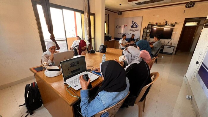 Des hommes et des femmes travaillent devant leur ordinateur dans un local.