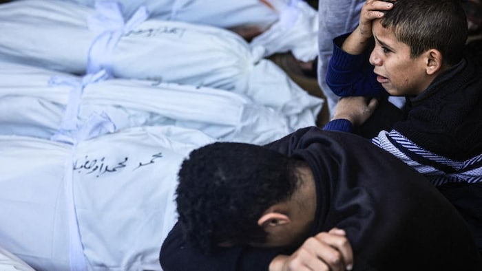 Niños palestinos lloran junto a los restos de sus familiares muertos por los bombardeos israelíes.