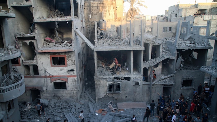 Des secouristes et des civils fouillent les décombres d'immeubles bombardés.