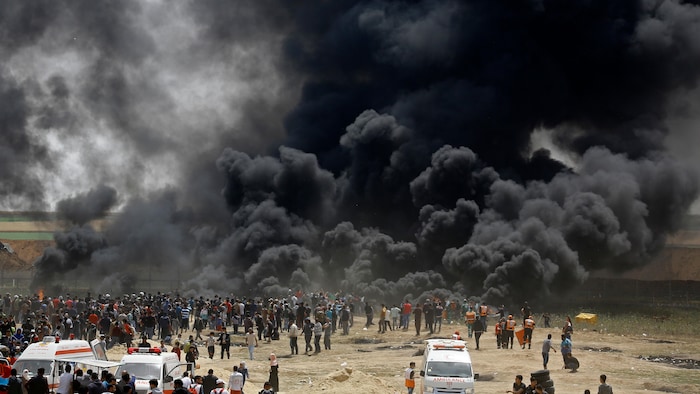 Des centaines de Palestiniens manifestent près d'une mur de fumée noire