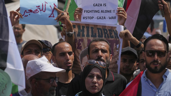 Gros plans sur des visages de manifestants et de pancartes dont une portant le slogan : 'Gaza se bat seule'.