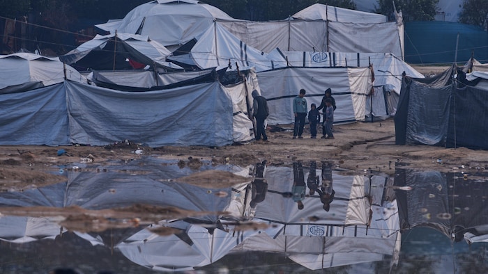 Des Palestiniens se tiennent à côté d'une zone inondée après de fortes pluies dans un camp de fortune pour personnes déplacées à Zawaida, dans le centre de la bande de Gaza.