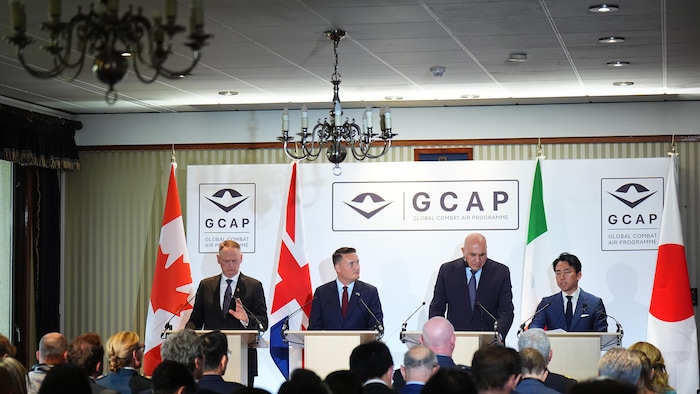 Les quatre hommes sont assis derrière une table.