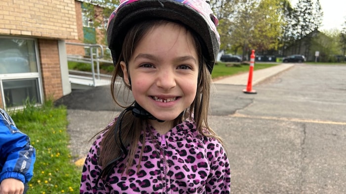 Fillette souriante avec un casque de vélo.