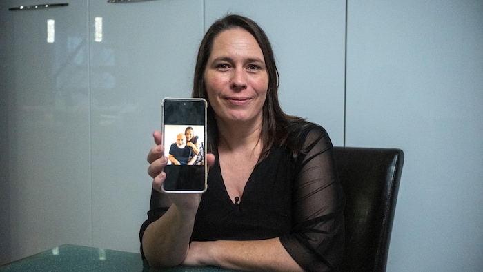 Geneviève Coutu tient un téléphone qui montre une photo d'elle avec son mari.