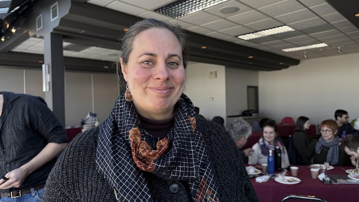 Genevieve Dick, souriante, devant une salle pleine de personnes.