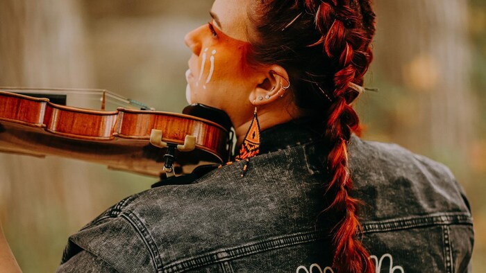 La violoniste est de dos avec son violon. 