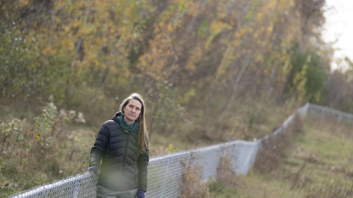 Geneviève Lussier s'appuie contre la clôture qui délimite le terrain.