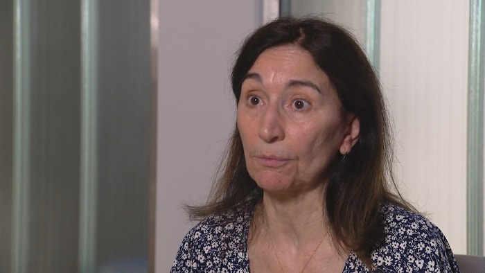Geneviève Seabrook, assise, regarde droit devant elle.
