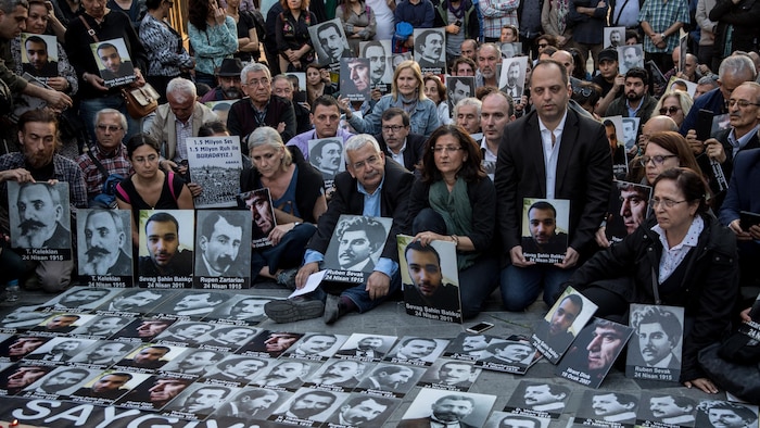 Des personnes brandissent des photos des victimes du génocide arménien de 1915 lors d'une cérémonie commémorative organisée pour leur rendre hommage le 24 avril 2018 à Istanbul, en Turquie. 