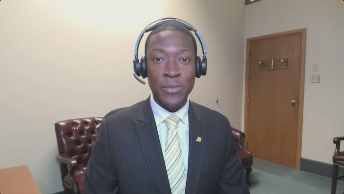 Un homme porte un casque avec microphone, assis devant un ordinateur. 