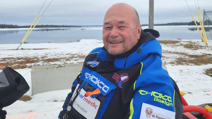Un innu assis sur sa motoneige devant une baie.