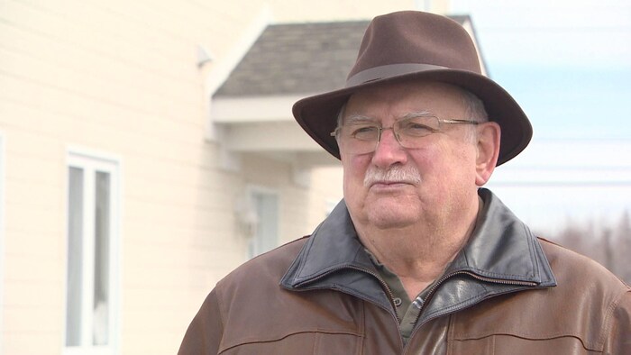Gérard Comeau à l'extérieur, coiffé d'un élégant chapeau brun.