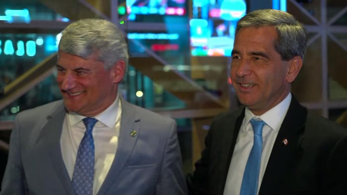 Deux hommes un à côté de l'autre, souriants.