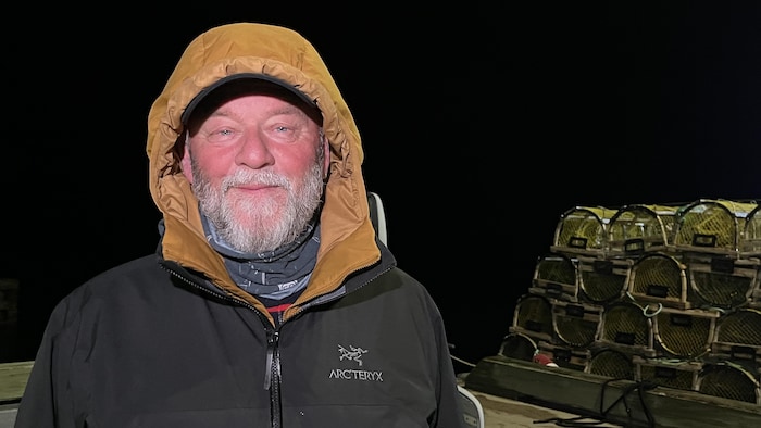 Germain Cyr, capitaine-propriétaire, devant des cages à homard.