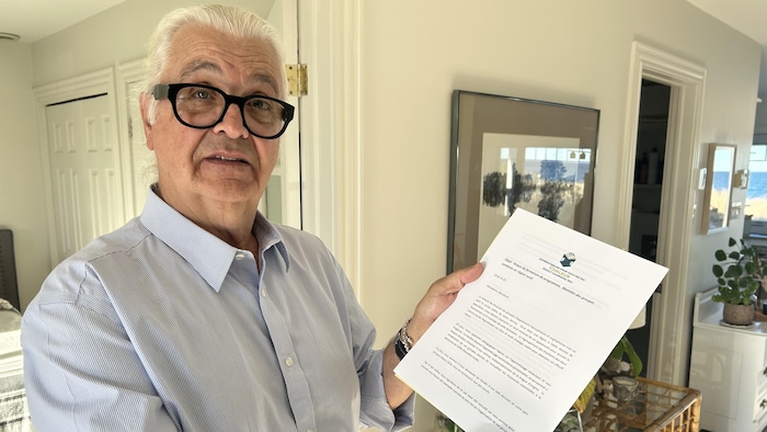 Un homme avec des lunettes noires tient une lettre