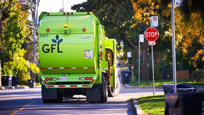 Un camion d’ordures vert à un arrêt.