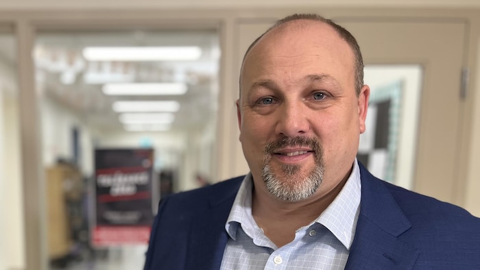 Un homme debout dans un couloir. Il regarde directement l'objectif pour une photo.