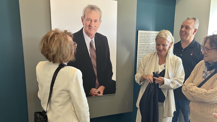 Une personne regarde une photo affichée sur le mur d'un local.