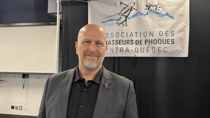 Gil Thériault, e directeur général de l’Association de chasseurs de phoques intra-Québec, est un homme chauve devant le drapeau de son association.