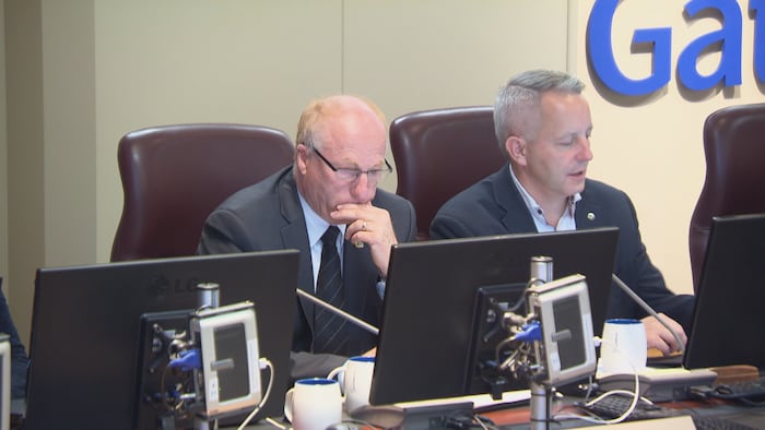 Le conseiller municipal Gilles Chagnon regarde un écran d'ordinateur dans la salle de réunion du conseil municipal de Gatineau. 