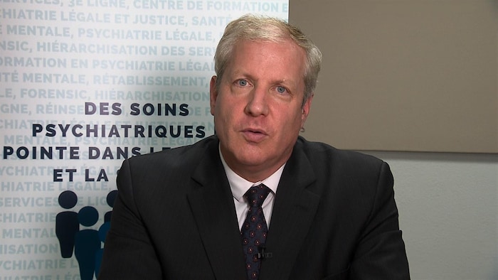 Gilles Chamberland, portant un veston-cravate, regarde droit dans la caméra.