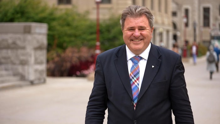 Un portrait de Gilles Levasseur vêtu d’un habit devant l’Université d’Ottawa.