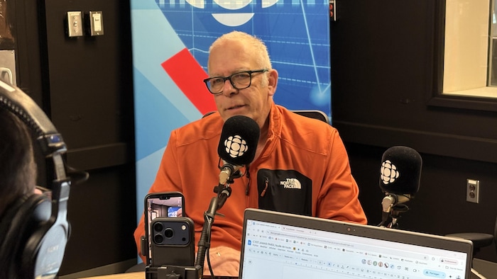 Un homme en entrevue en studio.