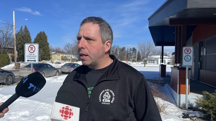 Un homme prend la parole devant des micros qui lui sont tendus.
