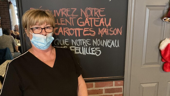 Ginette Tremblay est devant un menu affiché dans son restaurant.