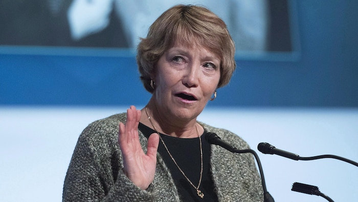 Madame Gallichan parle devant des microphones.
