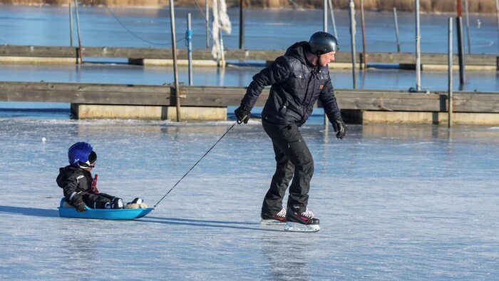 Un homme et un enfant patinent sur la glace.