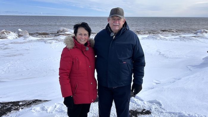 Armandine et Emmanuel Haché devant la mer. Ils portent des manteaux d'hiver. Il n'y a pas de glace sur l'eau.