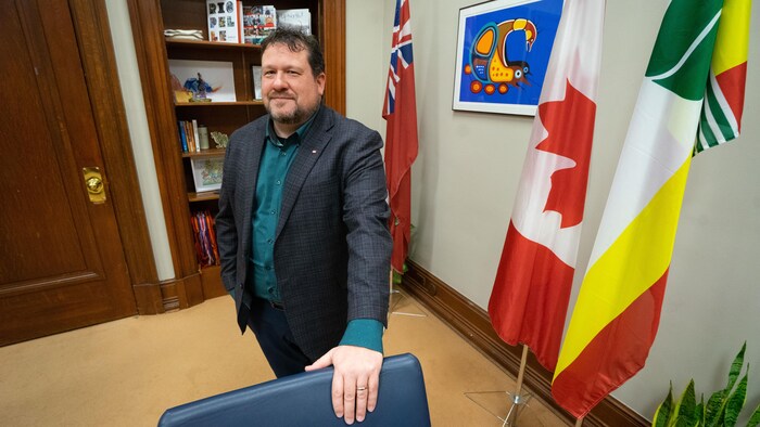 M. Simard s'appuie sur une chaise.