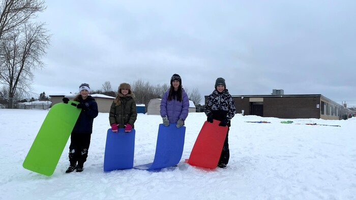 Quatre élèves sur une butte de neige à l'école St-Dominique a Sudbury.