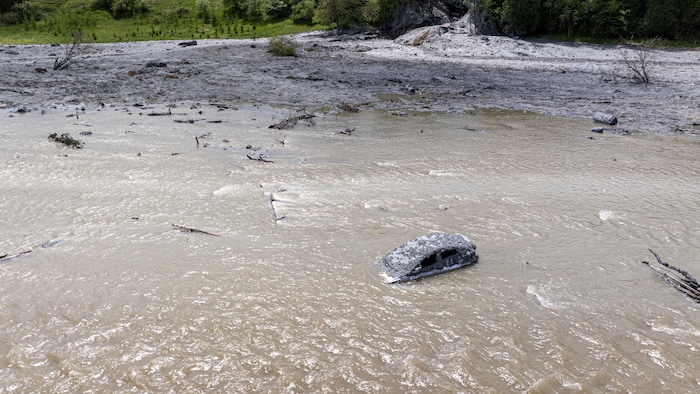 Une voiture immergée dans une rivière boueuse.