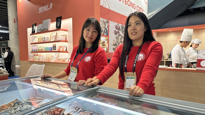 Deux représentantes d'une entreprise coréenne derrière leur kiosque.