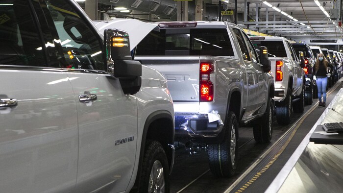 Des camionnettes Silverado dans la chaîne d’assemblage et une travailleuse à l’usine de GM à Oshawa, le 22 février 2022.
